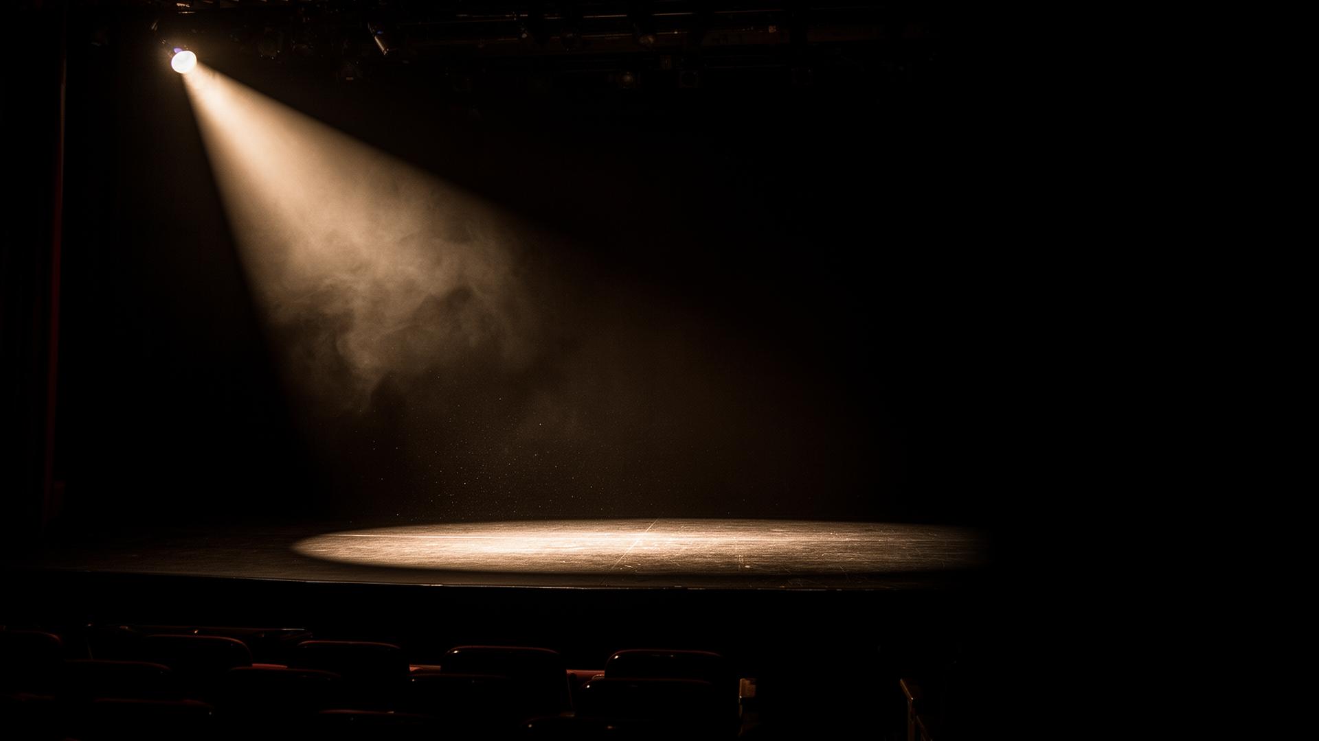 Empty stage lit by a single warm spotlight from the upper left